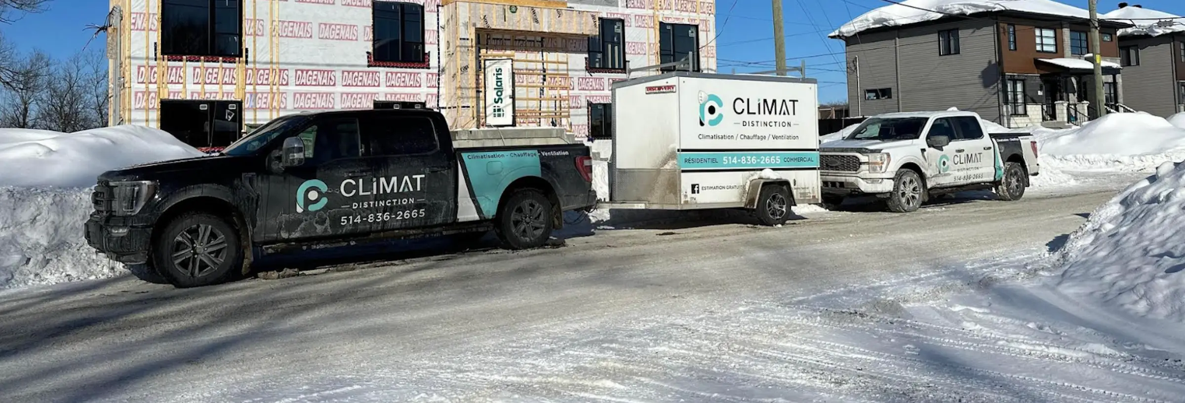 Camions et remorque de Climat Distinction stationnés devant une maison, en hiver